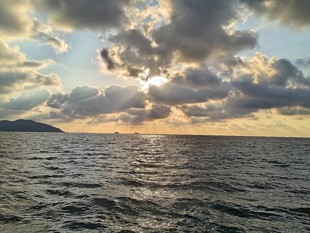 Late sun breaking through clouds over the sea at Teluk Senangin