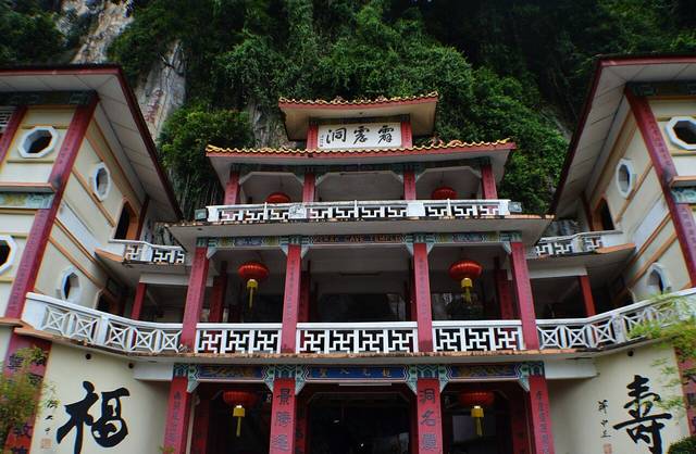Red and white tiered pavilion of Sam Poh Tong cave temple against the limestone hill