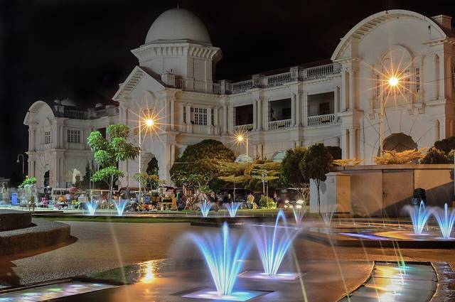 Ipoh Railway Station lit up at night with illuminated fountains in the foreground