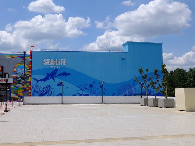 The blue outer wall of SEA LIFE Malaysia painted with sharks, fish and coral, next to the LEGOLAND Malaysia Resort