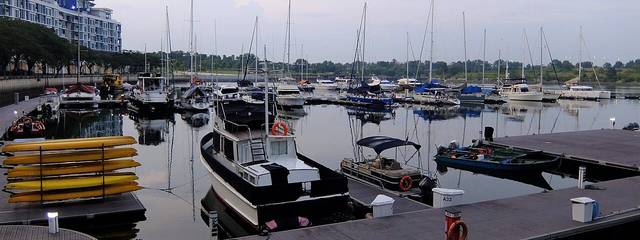 Yachts and motor boats moored at the Puteri Harbour marina in Iskandar Puteri, with a low-rise waterfront building on the left at dusk
