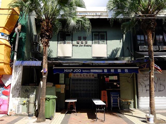 Green shophouse of Hiap Joo Bakery on Jalan Tan Hiok Nee with its blue 'since 1919' awning, photographed with the shutter closed in 2020