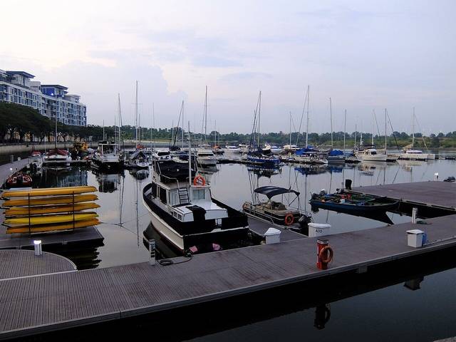 Yachts and boats moored at Puteri Harbour marina in Iskandar Puteri at dusk, with apartment blocks along the waterfront