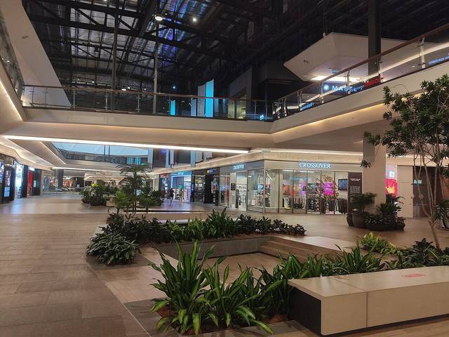 Inside Mid Valley Southkey: a wide mall walkway with planters, shopfronts and a glass roof above two upper floors