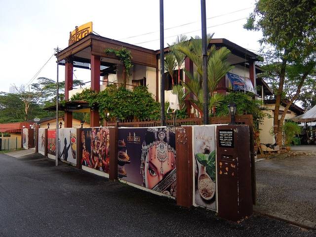 Chakra Restaurant in Kampung Bahru, Johor Bahru, a two-storey bungalow with red pillars behind a fence painted with Indian food and dance images