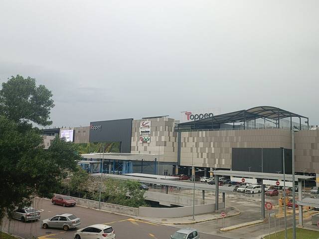 Toppen Shopping Centre in Tebrau seen across a car park and covered bus stop on a grey day, with the Toppen sign on the building