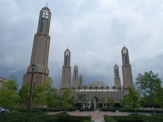 The Mosque of Kota Iskandar with its tall pale minarets and a latticed dome behind landscaped gardens