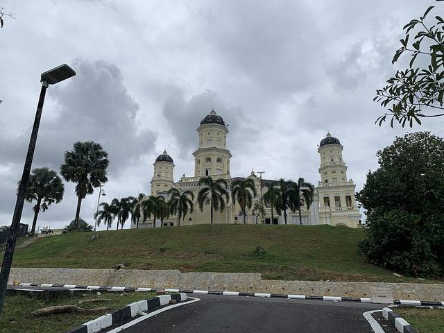 The Sultan Abu Bakar State Mosque on its hill in Johor Bahru, with three domed towers and a row of palm trees