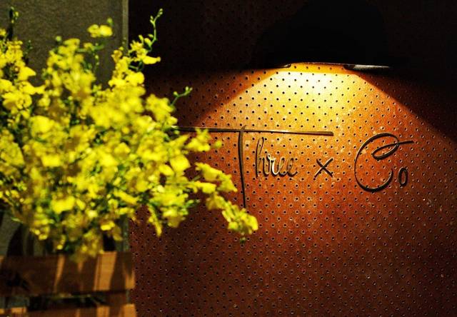 Spotlit Three X Co name sign on the pegboard wall inside the bar at Bangsar Shopping Centre, Kuala Lumpur