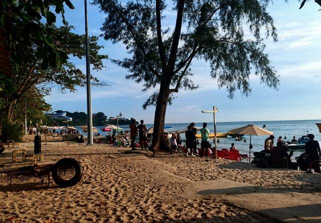 波德申Teluk Kemang海滩的沙滩和海中，有游客、遮阳伞和一艘香蕉船