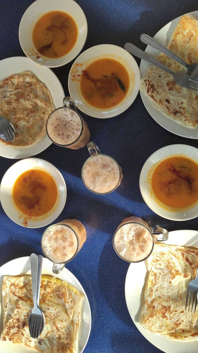 Glasses of teh tarik with roti canai and curry at breakfast, among the best drinks in Kuala Lumpur