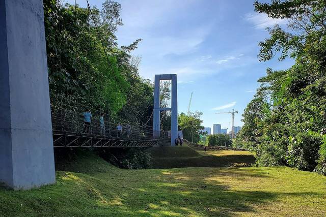 Para pejalan menyeberangi jembatan gantung di atas lapangan berumput di Bukit Gasing, Petaling Jaya