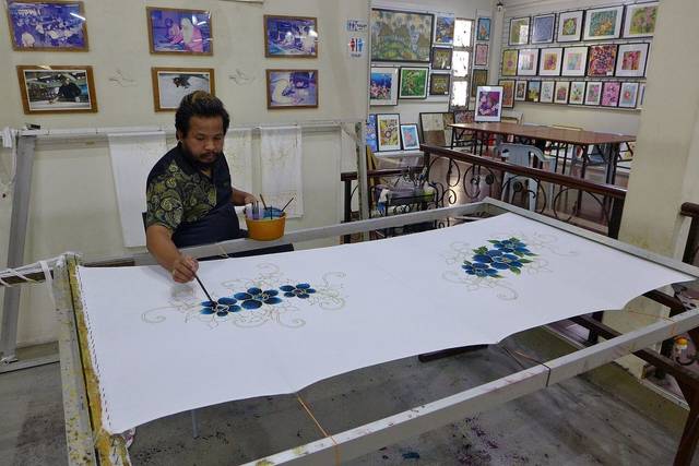 Artisan hand-painting batik on a stretched cloth in the Jadi Batek Gallery workshop, Kuala Lumpur
