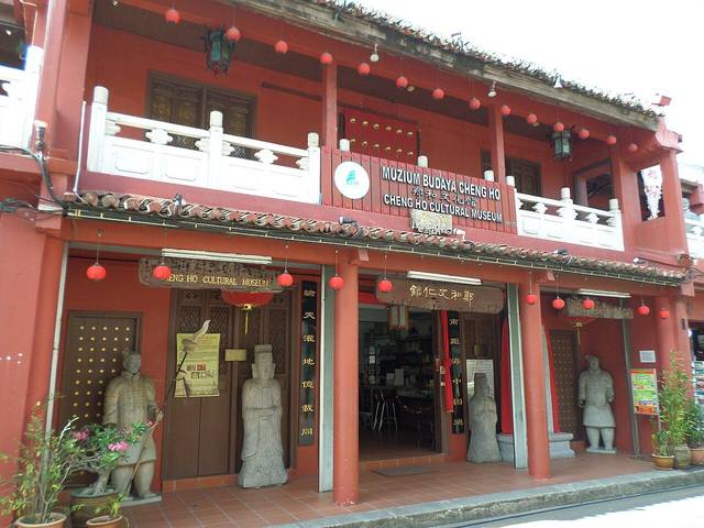 The red two-storey front of the Cheng Ho Cultural Museum with lanterns and stone figures at the entrance