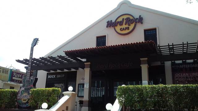 The white gabled front of Hard Rock Cafe Melaka with a giant guitar sign, steps and a live music banner