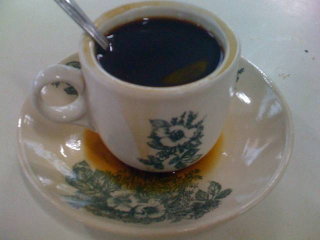 A cup of kopi O, sweet black coffee, in a flower-patterned kopitiam cup and saucer of the kind used for Melaka drinks such as Hainanese kopi