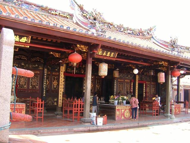 The carved and painted front hall of Cheng Hoon Teng Temple with red lanterns and an altar table