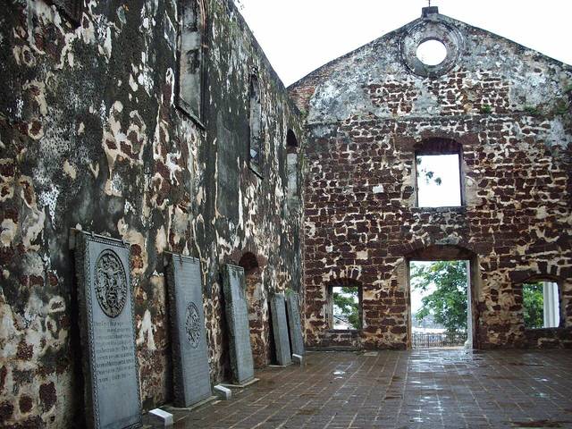 Inside the roofless ruins of St Paul's Church in Melaka, with old engraved tombstones standing along the laterite walls