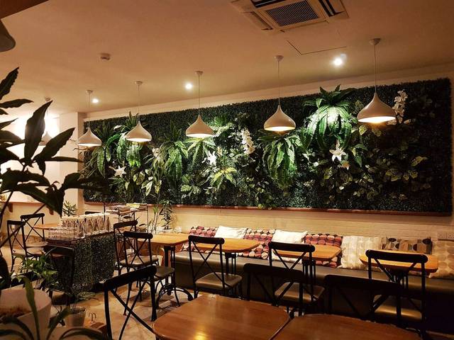 Seating area with a green plant wall inside Constant Gardener Coffee on Lebuh Light, George Town, Penang