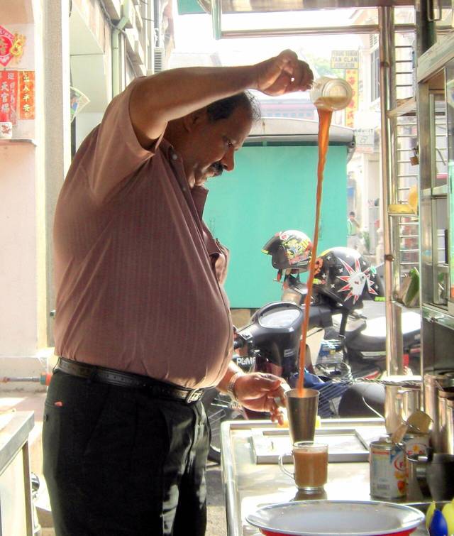 A tea maker pulling teh tarik between two cups, a drink served at most kopitiams and mamak shops on this Selangor drinks list