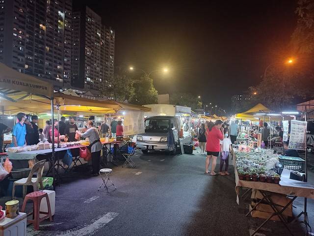 Stalls under yellow canopies and shoppers on a closed street at night at a pasar malam in Seri Kembangan, one of the night markets in Selangor