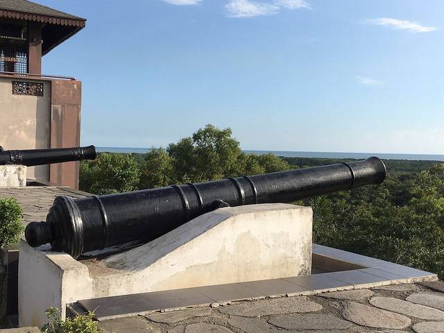 Old black cannon on the hilltop at Bukit Melawati pointing over the trees towards the Strait of Malacca, Kuala Selangor