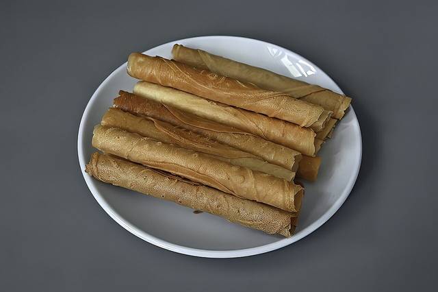 Rolled kuih kapit biscuits on a plate