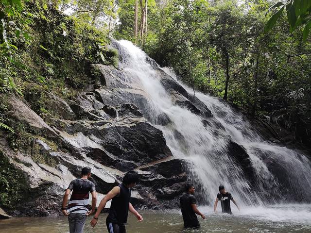 Visitors standing in the pool below a tier of Kanching Falls in the rainforest near Rawang, Selangor